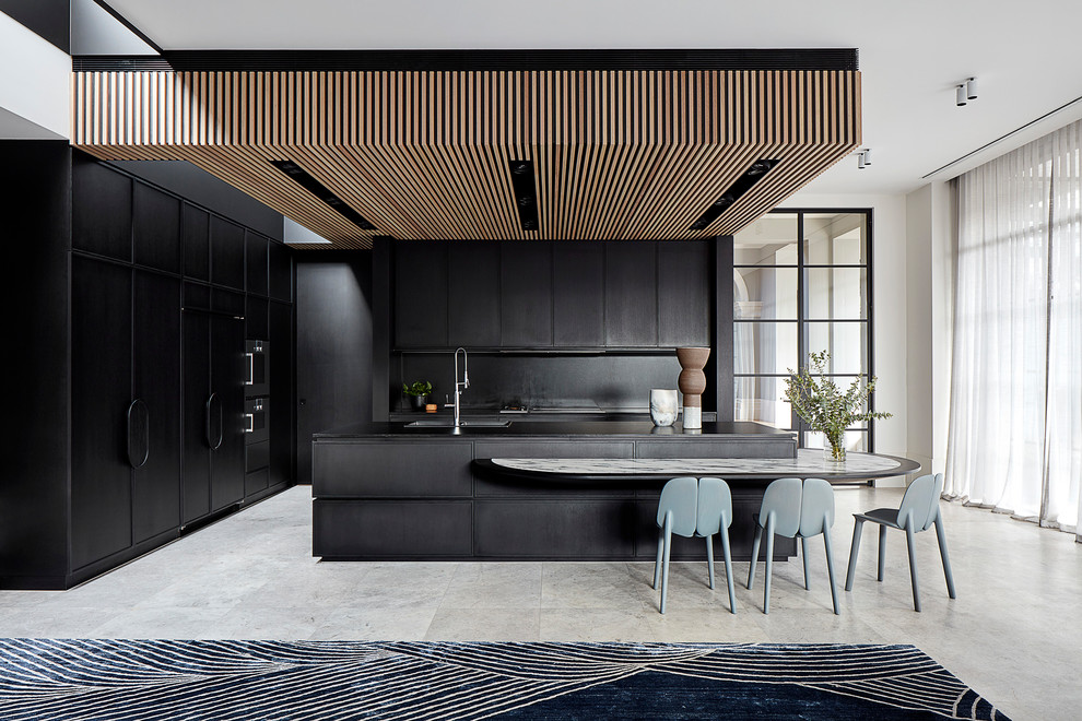 Photo of an expansive modern open plan kitchen in Melbourne with a double-bowl sink, shaker cabinets, black cabinets, granite benchtops, black splashback, stone slab splashback, black appliances, limestone floors, with island, grey floor and black benchtop.