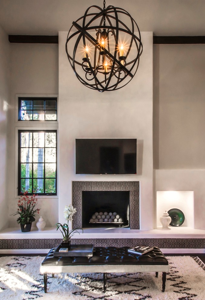 This is an example of an expansive mediterranean open concept family room in Santa Barbara with white walls, dark hardwood floors, a standard fireplace, a tile fireplace surround and a wall-mounted tv.