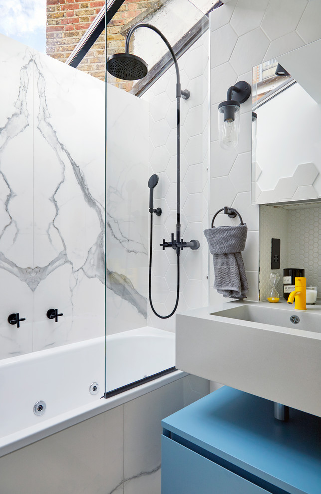 This is an example of a small contemporary bathroom in London with a shower/bathtub combo, a one-piece toilet, white tile, ceramic tile, white walls, a hinged shower door and flat-panel cabinets.