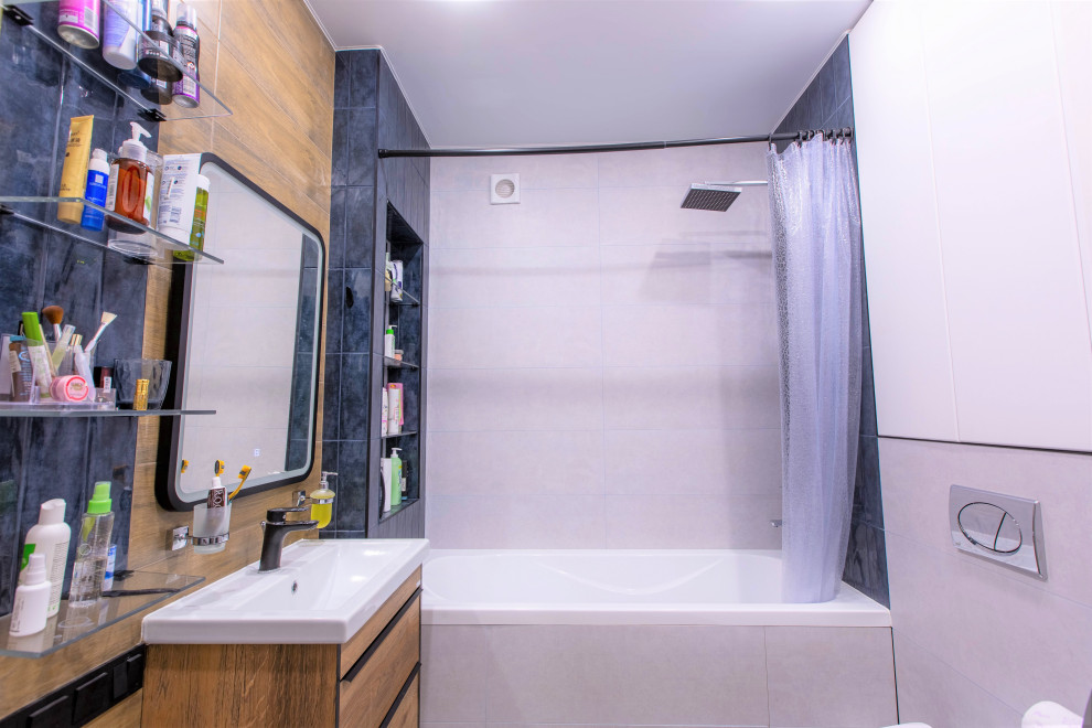 Inspiration för små moderna en-suite badrum, med släta luckor, skåp i mellenmörkt trä, ett badkar i en alkov, en dusch/badkar-kombination, en vägghängd toalettstol, blå kakel, beige väggar, klinkergolv i porslin, ett nedsänkt handfat, grått golv och dusch med duschdraperi