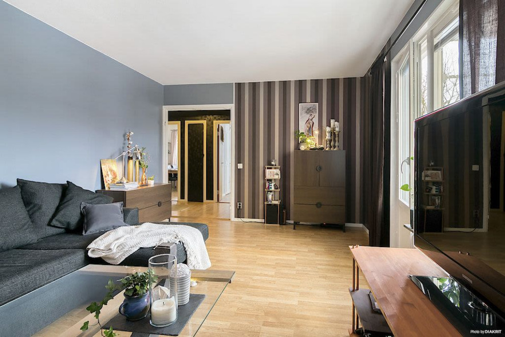 Idée de décoration pour un petit salon chalet fermé avec une salle de réception, un mur bleu, un sol en bois brun, un téléviseur indépendant, un sol beige et du papier peint.