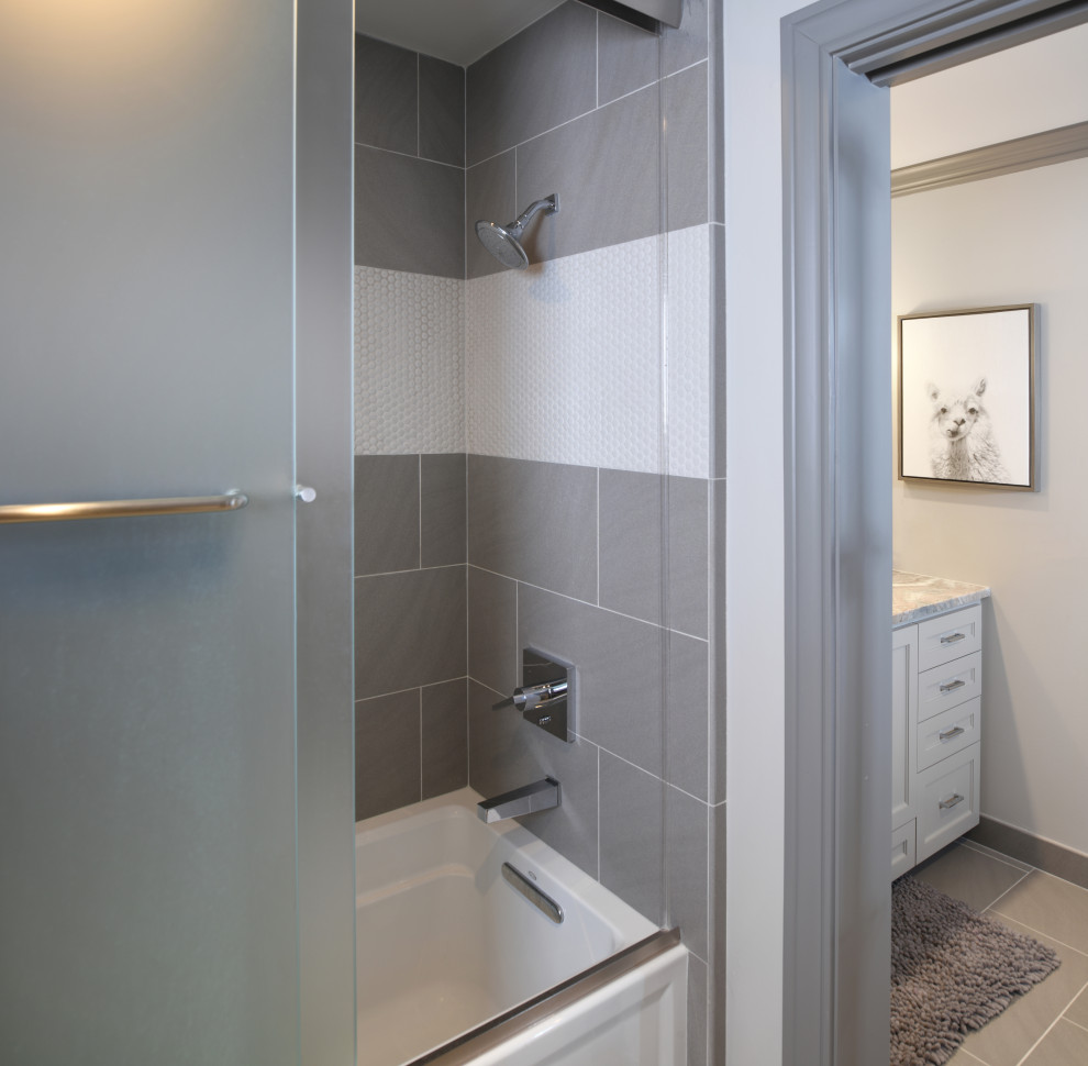 This is an example of a mid-sized transitional kids bathroom in Houston with shaker cabinets, grey cabinets, an alcove tub, a shower/bathtub combo, a one-piece toilet, multi-coloured tile, mosaic tile, grey walls, porcelain floors, an undermount sink, quartzite benchtops, grey floor, a sliding shower screen and multi-coloured benchtops.