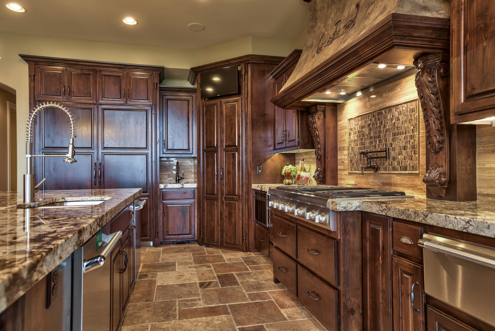 Large mediterranean l-shaped open plan kitchen in Omaha with a double-bowl sink, raised-panel cabinets, dark wood cabinets, granite benchtops, beige splashback, stone tile splashback, stainless steel appliances, slate floors, with island and beige floor.