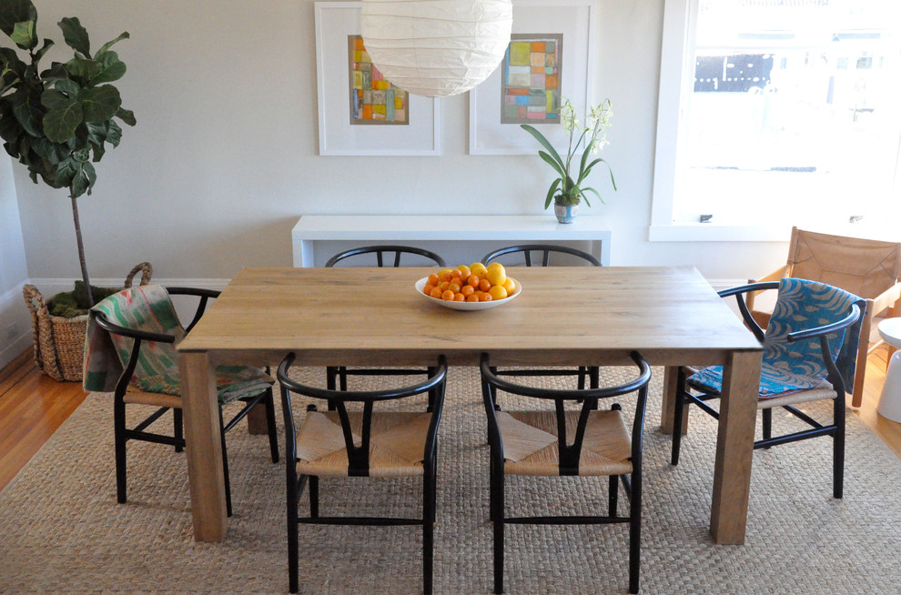 This is an example of an eclectic dining room in San Francisco with white walls and medium hardwood floors.