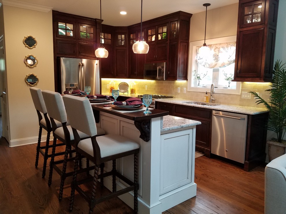 This is an example of a mid-sized arts and crafts galley eat-in kitchen in Bridgeport with a double-bowl sink, recessed-panel cabinets, dark wood cabinets, granite benchtops, beige splashback, stone tile splashback, stainless steel appliances, medium hardwood floors and with island.