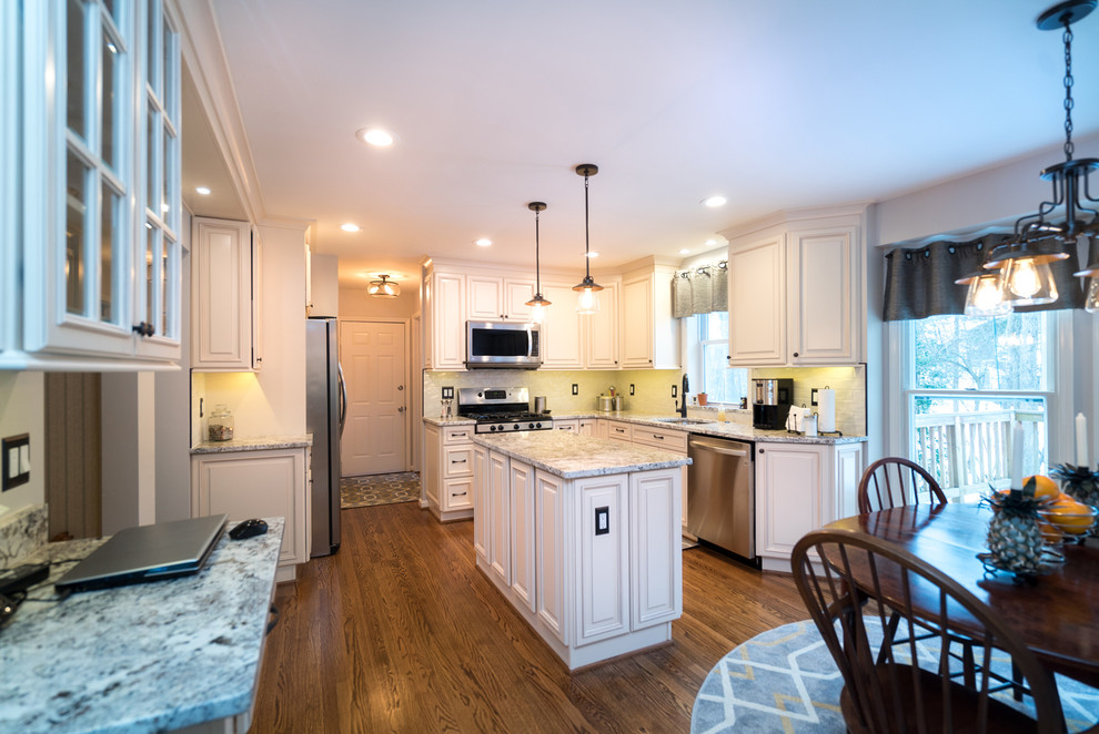 Design ideas for a mid-sized traditional l-shaped eat-in kitchen in DC Metro with an undermount sink, raised-panel cabinets, white cabinets, granite benchtops, white splashback, porcelain splashback, stainless steel appliances, dark hardwood floors and with island.
