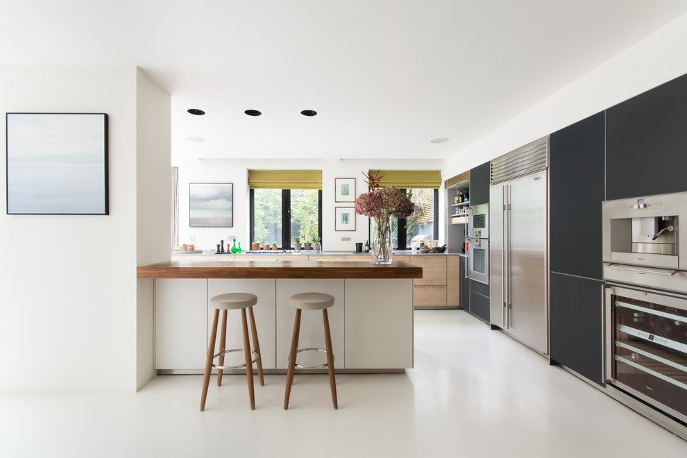 Photo of a contemporary kitchen in London with flat-panel cabinets, black cabinets, wood benchtops, window splashback, stainless steel appliances, a peninsula and white floor.