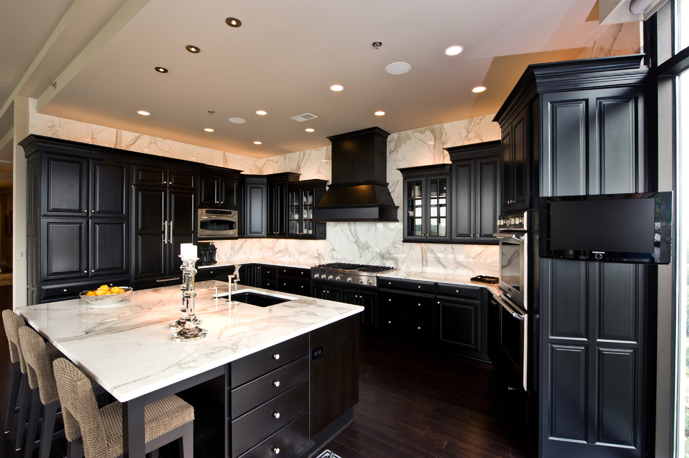 Photo of a traditional kitchen in Minneapolis with raised-panel cabinets, black cabinets, marble benchtops, white splashback, panelled appliances and marble splashback.