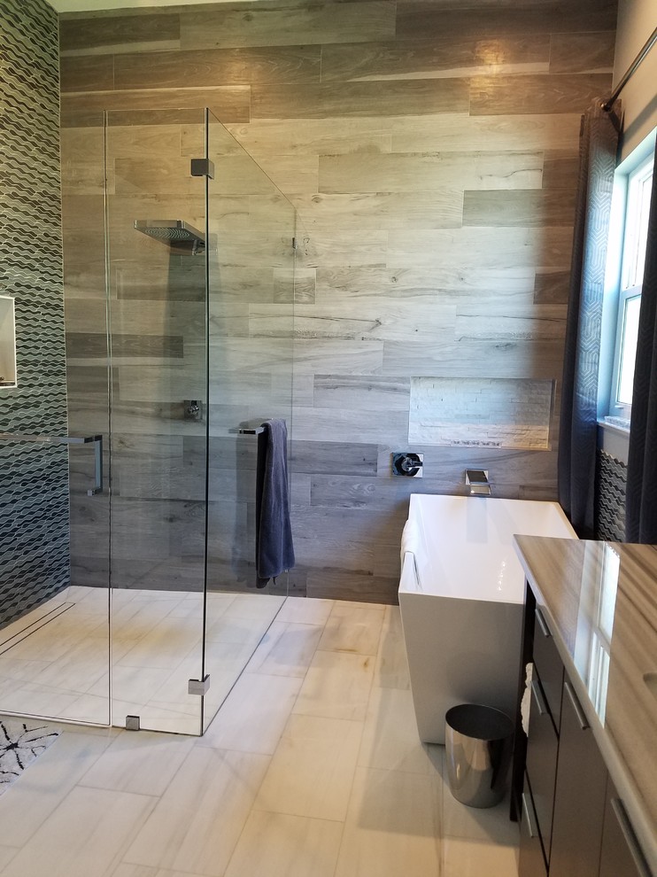Design ideas for a mid-sized transitional master bathroom in Miami with flat-panel cabinets, black cabinets, a freestanding tub, a corner shower, a one-piece toilet, gray tile, porcelain tile, grey walls, marble floors, an undermount sink, marble benchtops, white floor and a hinged shower door.