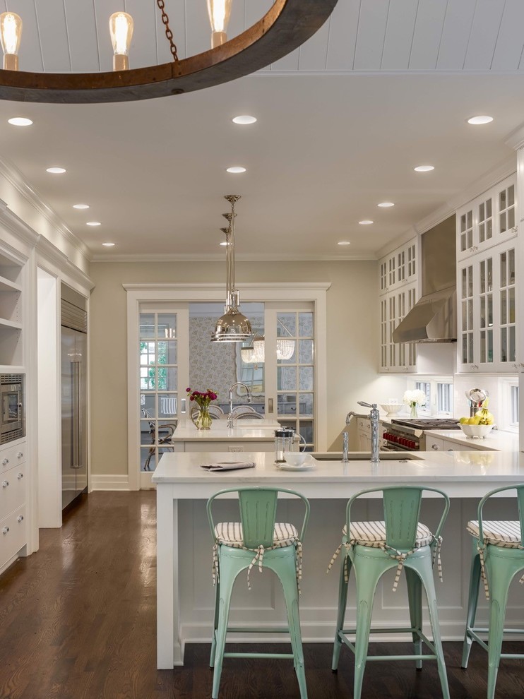 Design ideas for a country l-shaped kitchen in Chicago with an undermount sink, glass-front cabinets, white cabinets, stainless steel appliances, dark hardwood floors and with island.