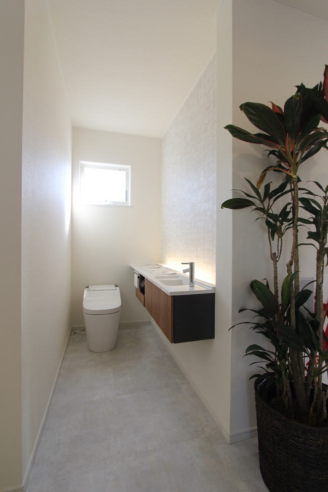 This is an example of a small country powder room in Other with a one-piece toilet, white walls, vinyl floors and grey floor.