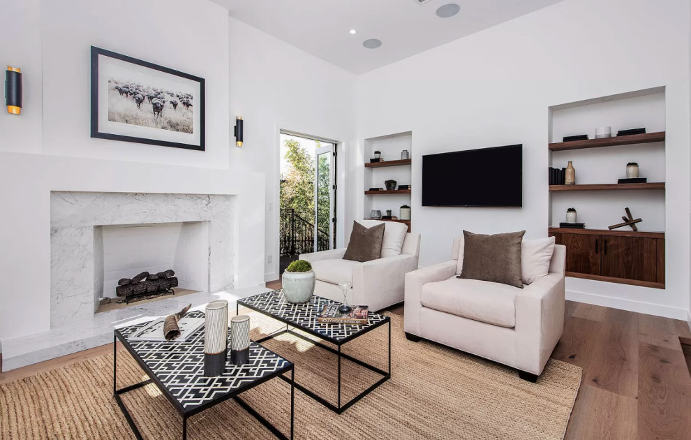 Photo of a large transitional formal open concept living room in Los Angeles with white walls, medium hardwood floors, a standard fireplace, a tile fireplace surround, a freestanding tv and beige floor.