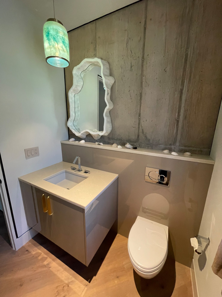 Inspiration for a contemporary cloakroom in Charleston with beige cabinets, a wall mounted toilet, glass sheet walls, grey walls, brown floors and a floating vanity unit.