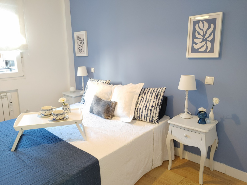 Imagen de dormitorio principal nórdico de tamaño medio con paredes azules, suelo de madera clara y suelo beige