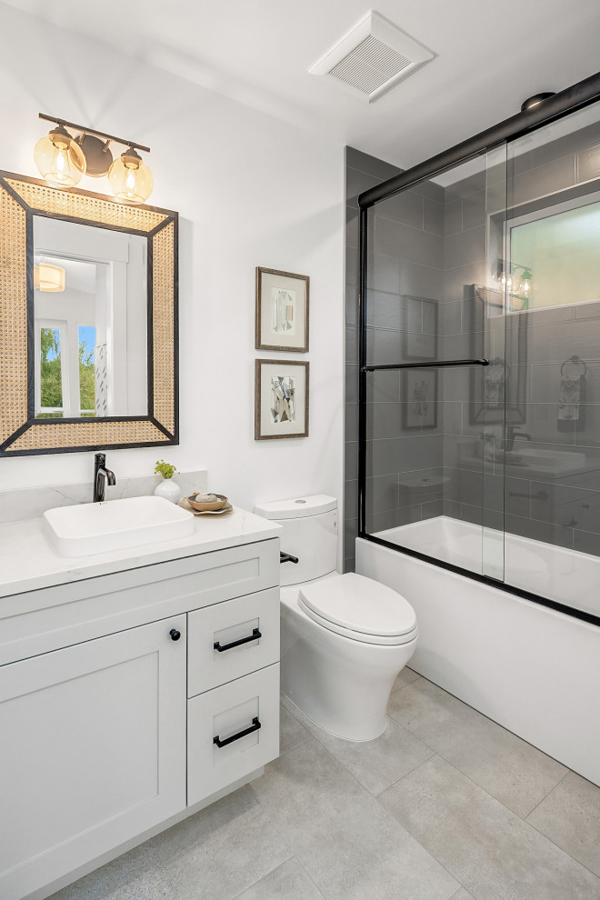 Small beach style kids bathroom in Seattle with recessed-panel cabinets, grey cabinets, an alcove tub, a two-piece toilet, black tile, porcelain tile, white walls, porcelain floors, a drop-in sink, quartzite benchtops, grey floor, a sliding shower screen, white benchtops, a single vanity and a built-in vanity.