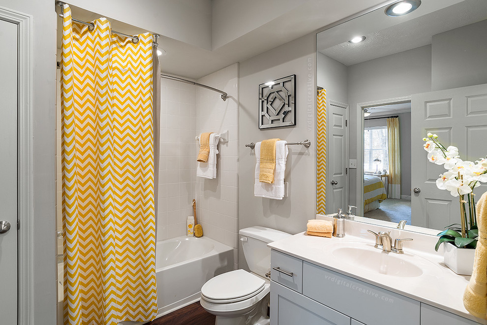 Inspiration for a contemporary master bathroom in Atlanta with flat-panel cabinets, white cabinets, an alcove tub, a shower/bathtub combo, a two-piece toilet, white tile, ceramic tile, grey walls, dark hardwood floors, an integrated sink and granite benchtops.