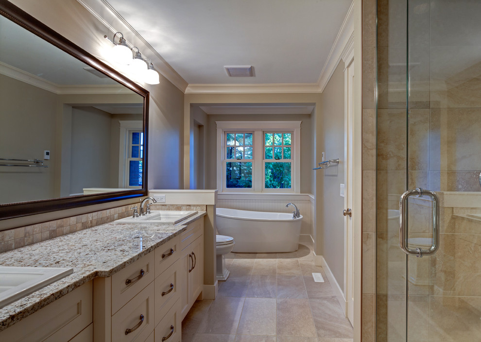 Inspiration for a mid-sized traditional master bathroom in Calgary with a drop-in sink, recessed-panel cabinets, white cabinets, granite benchtops, a freestanding tub, a one-piece toilet, beige tile, beige walls and porcelain floors.