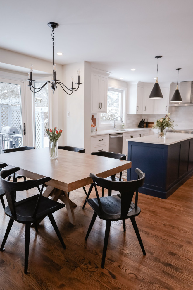 Eat-in kitchen - small transitional u-shaped medium tone wood floor and brown floor eat-in kitchen idea in Ottawa with an undermount sink, shaker cabinets, white cabinets, quartz countertops, white backsplash, subway tile backsplash, stainless steel appliances, an island and white countertops