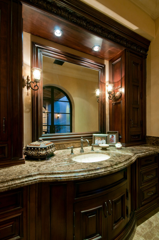 This is an example of an expansive mediterranean kids bathroom in Phoenix with furniture-like cabinets, beige cabinets, a curbless shower, a one-piece toilet, beige tile, stone tile, beige walls, travertine floors, a drop-in sink and granite benchtops.