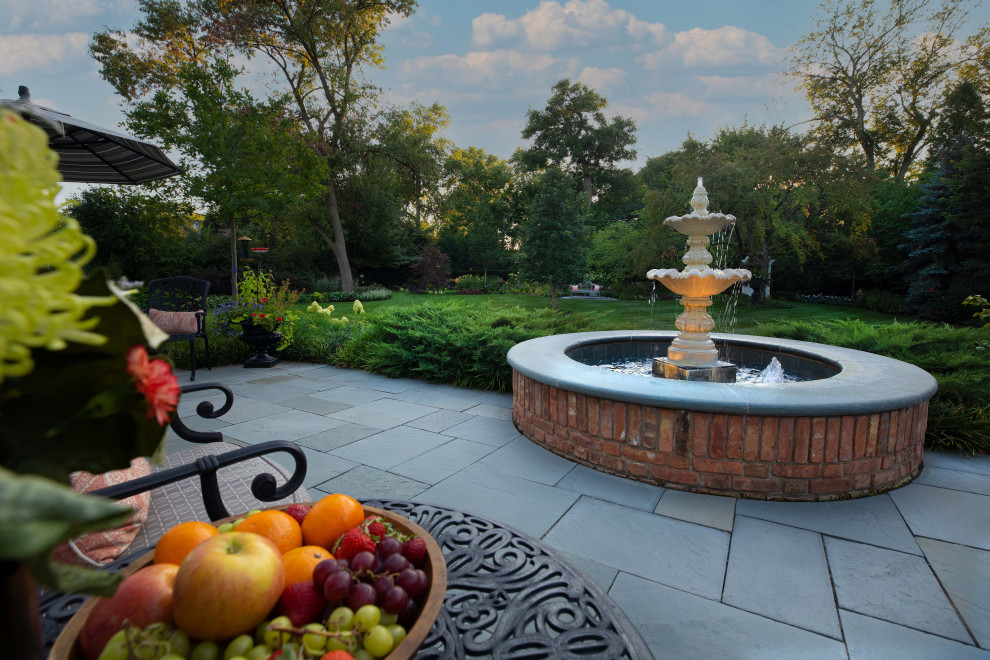 Large traditional backyard patio in Chicago with with fireplace and natural stone pavers.