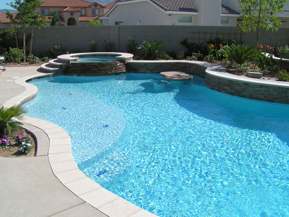 This is an example of a mid-sized backyard custom-shaped natural pool in Las Vegas with a water slide and concrete slab.