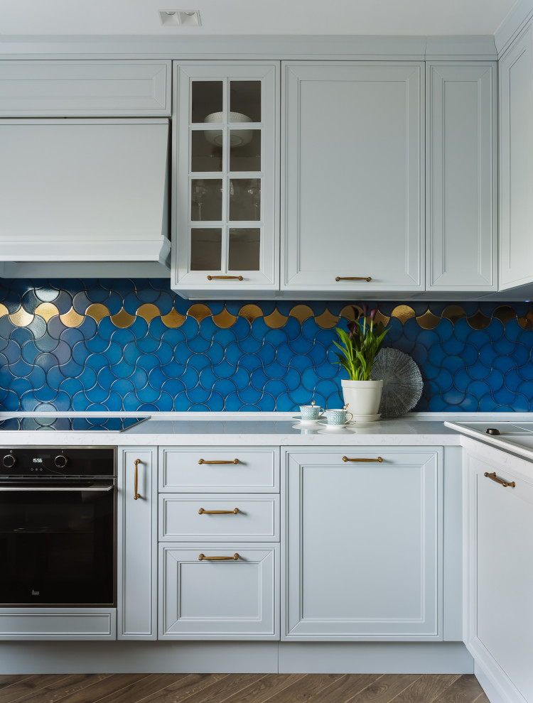 Mid-sized transitional l-shaped separate kitchen in Moscow with a drop-in sink, raised-panel cabinets, turquoise cabinets, quartz benchtops, blue splashback, ceramic splashback, black appliances, porcelain floors, brown floor and white benchtop.