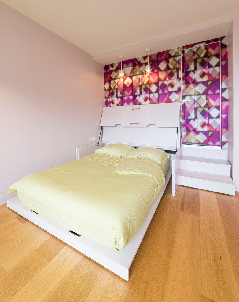 Small contemporary master bedroom in Paris with pink walls, light hardwood floors, no fireplace and brown floor.