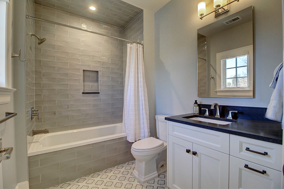 Design ideas for an expansive traditional family bathroom in Denver with recessed-panel cabinets, white cabinets, an alcove bath, a shower/bath combination, a one-piece toilet, grey tiles, metro tiles, white walls, ceramic flooring, a submerged sink, onyx worktops, white floors, a shower curtain, black worktops, a single sink and a built in vanity unit.