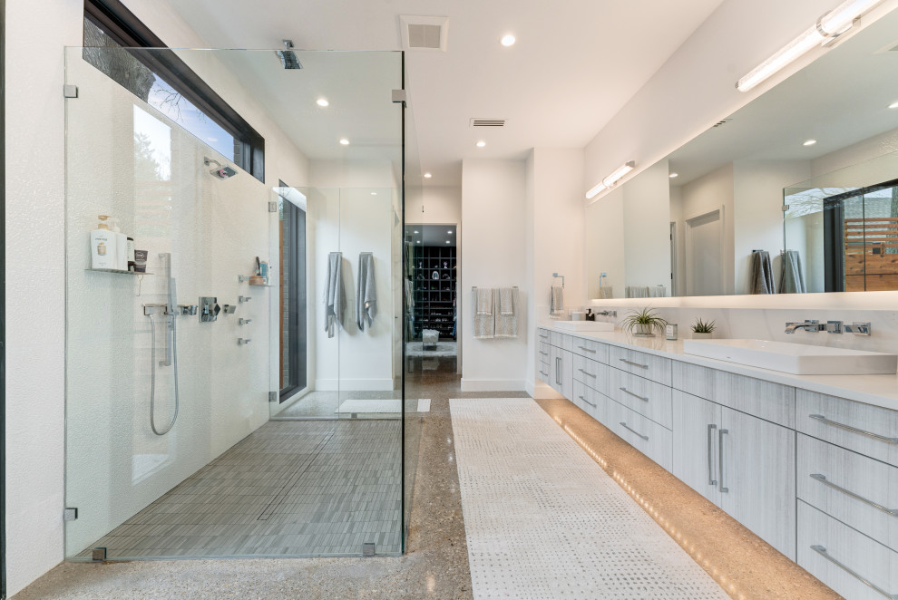 Idéer för att renovera ett funkis vit vitt en-suite badrum, med släta luckor, grå skåp, en kantlös dusch, vit kakel, porslinskakel, vita väggar, betonggolv, ett fristående handfat, bänkskiva i kvarts, grått golv och dusch med gångjärnsdörr