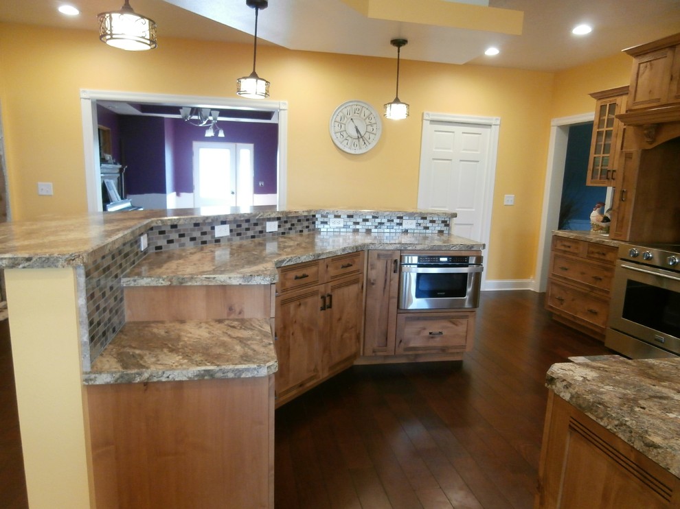 Example of a large mountain style single-wall dark wood floor and brown floor eat-in kitchen design with shaker cabinets, medium tone wood cabinets, laminate countertops, metallic backsplash, stainless steel appliances and two islands