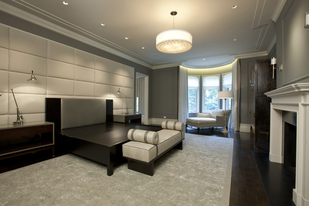 Inspiration for a large transitional master bedroom in Chicago with grey walls, dark hardwood floors, a standard fireplace and a wood fireplace surround.