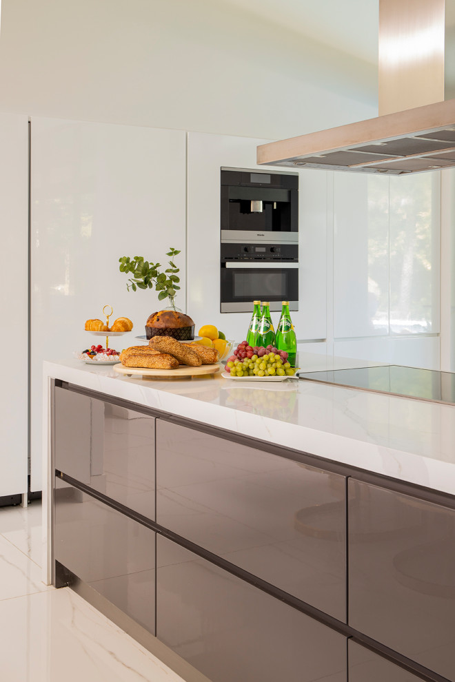 Mid-sized contemporary galley eat-in kitchen in Miami with an undermount sink, flat-panel cabinets, white cabinets, quartzite benchtops, white splashback, marble splashback, stainless steel appliances, marble floors, with island, white floor and white benchtop.