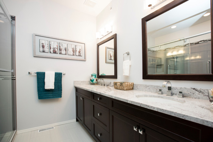 Mid-sized traditional master bathroom in Calgary with an undermount sink, shaker cabinets, dark wood cabinets, granite benchtops, a corner shower, a one-piece toilet, gray tile, ceramic tile, grey walls, ceramic floors, a sliding shower screen and grey floor.