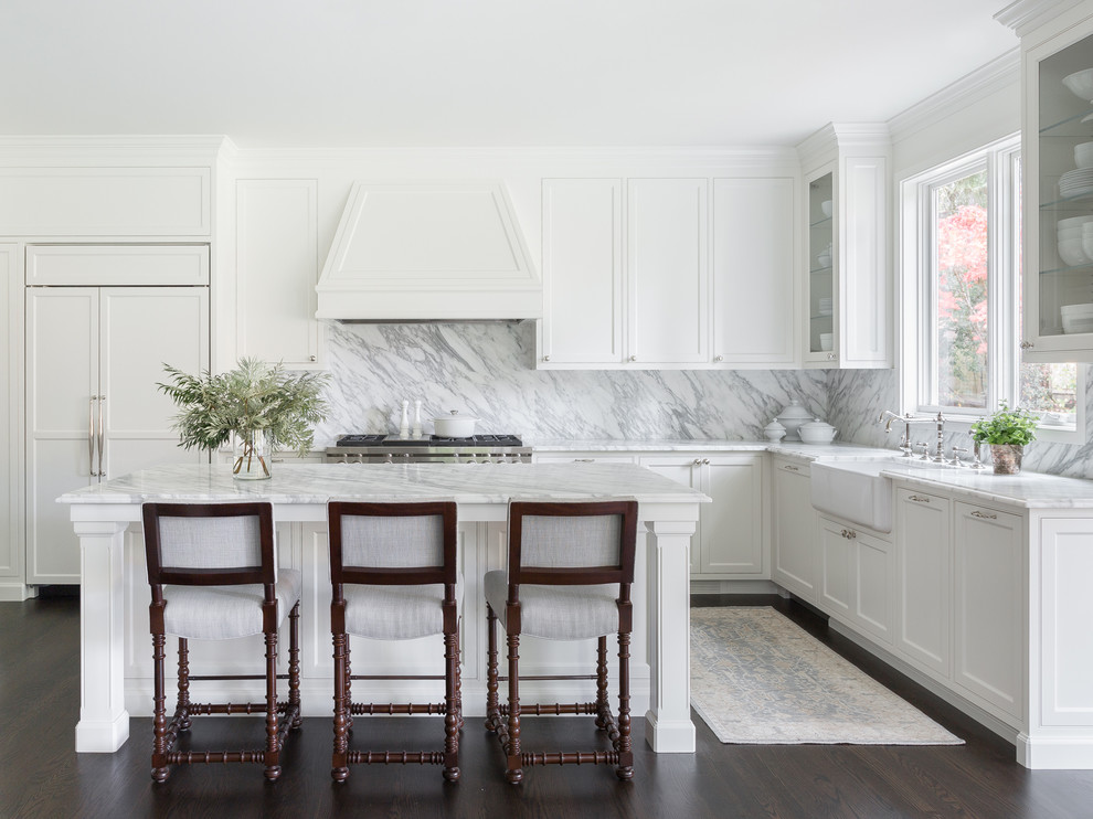 Example of a transitional l-shaped dark wood floor kitchen design in Seattle with a farmhouse sink, shaker cabinets, white cabinets, white backsplash, stone slab backsplash, paneled appliances, an island and white countertops