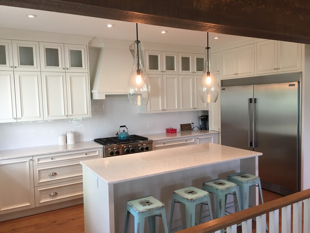 This is an example of a mid-sized transitional u-shaped eat-in kitchen in Calgary with recessed-panel cabinets, white cabinets, marble benchtops, white splashback, porcelain splashback, stainless steel appliances, medium hardwood floors and with island.