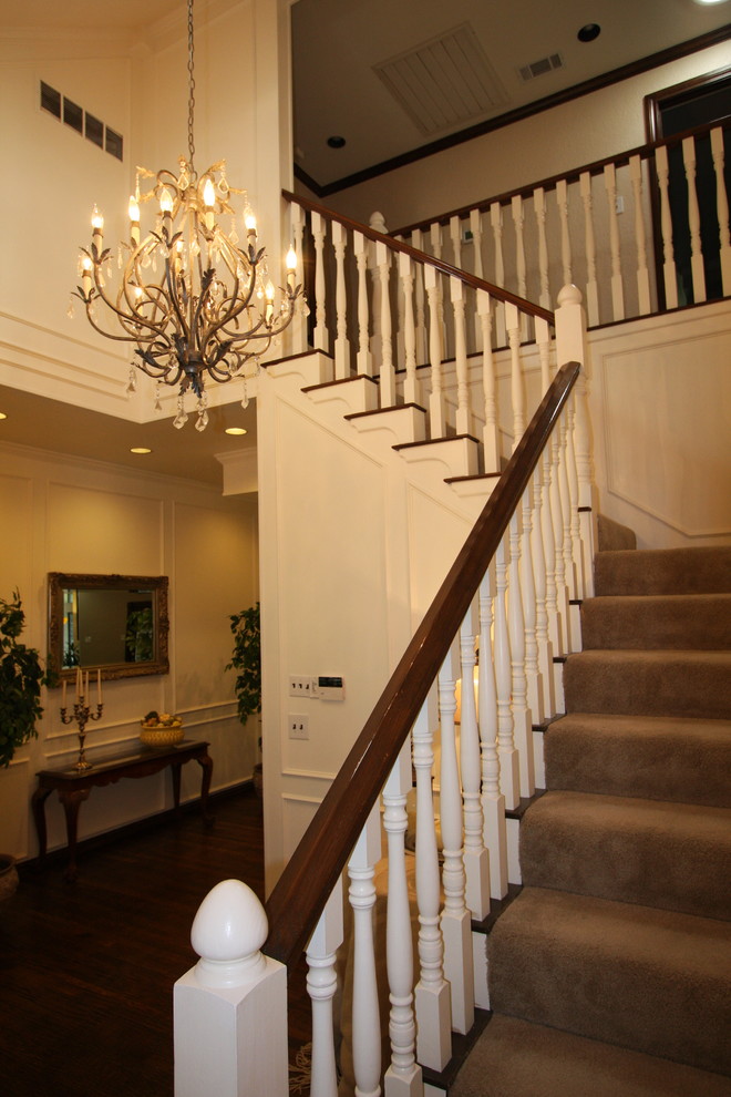 Traditional carpeted l-shaped staircase in Dallas with carpet risers and wood railing.