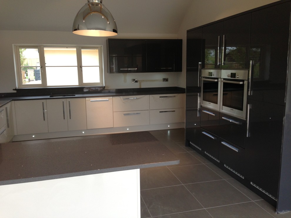 This is an example of a large contemporary u-shaped eat-in kitchen in Cambridgeshire with an undermount sink, flat-panel cabinets, grey cabinets, quartzite benchtops, stainless steel appliances and ceramic floors.
