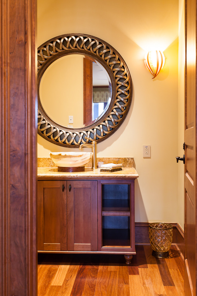 Design ideas for a mid-sized traditional powder room in Charleston with a vessel sink, medium wood cabinets, granite benchtops, yellow walls, medium hardwood floors and shaker cabinets.