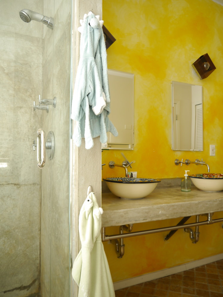 This is an example of a mid-sized eclectic master bathroom in New York with a vessel sink, concrete benchtops, terra-cotta tile, yellow walls and concrete floors.