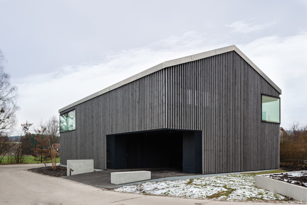 This is an example of a mid-sized contemporary two-storey grey exterior in Munich with wood siding and a gable roof.