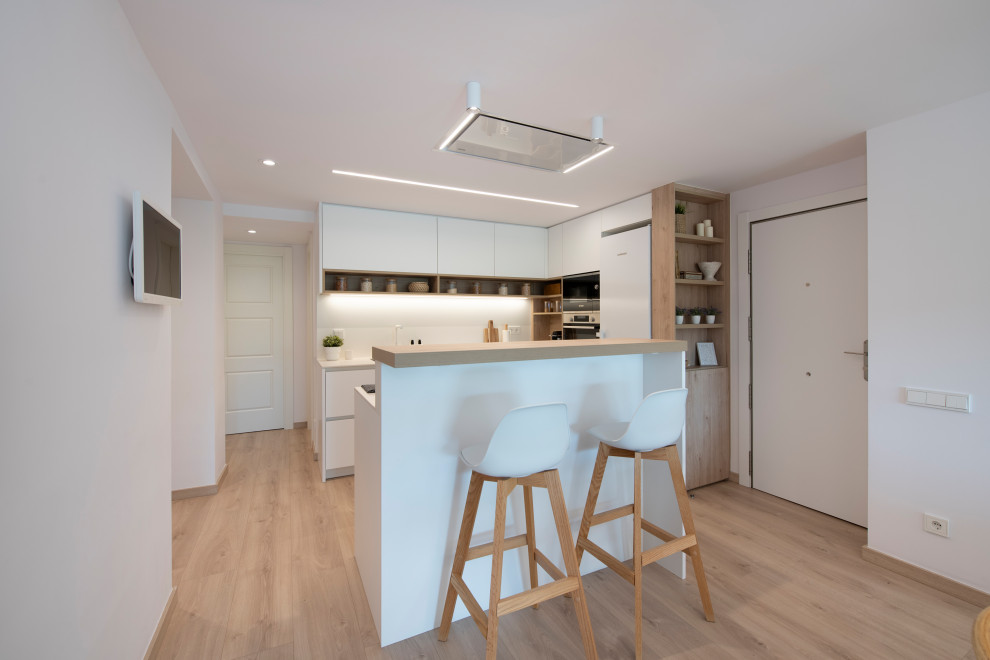 Design ideas for a mid-sized scandinavian l-shaped open plan kitchen in Barcelona with an undermount sink, flat-panel cabinets, white cabinets, quartz benchtops, white splashback, engineered quartz splashback, stainless steel appliances, with island, white benchtop, medium hardwood floors and brown floor.