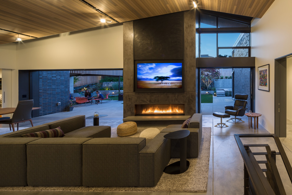 This is an example of a large midcentury open concept living room in Seattle with white walls, concrete floors, a standard fireplace, a plaster fireplace surround and a concealed tv.