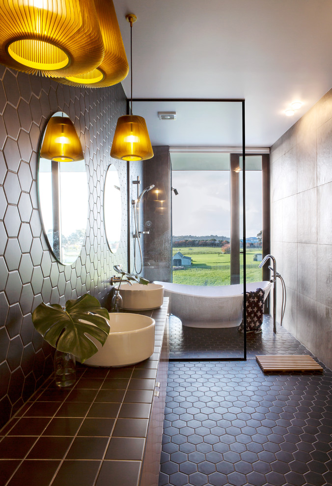 This is an example of a contemporary master wet room bathroom in Auckland with a freestanding tub, brown tile, brown walls, a vessel sink, brown floor, an open shower and brown benchtops.