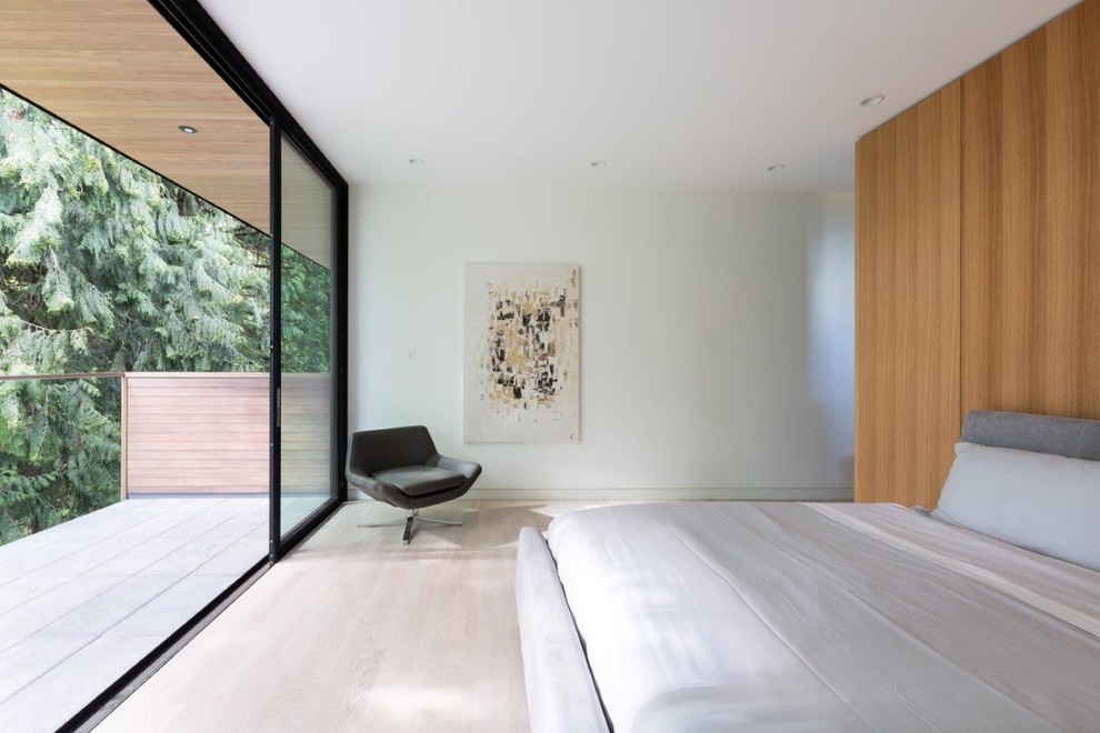 This is an example of a modern master bedroom in Vancouver with white walls, light hardwood floors and no fireplace.