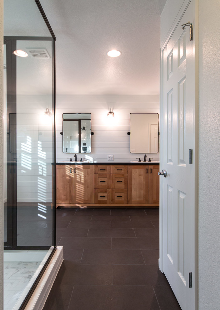 Mid-sized country master bathroom in Other with shaker cabinets, medium wood cabinets, a double shower, a one-piece toilet, white tile, ceramic tile, white walls, porcelain floors, a drop-in sink, granite benchtops and black floor.