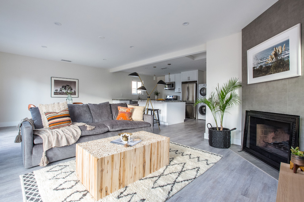 This is an example of a transitional formal open concept living room in San Diego with white walls, a standard fireplace, a brick fireplace surround and grey floor.