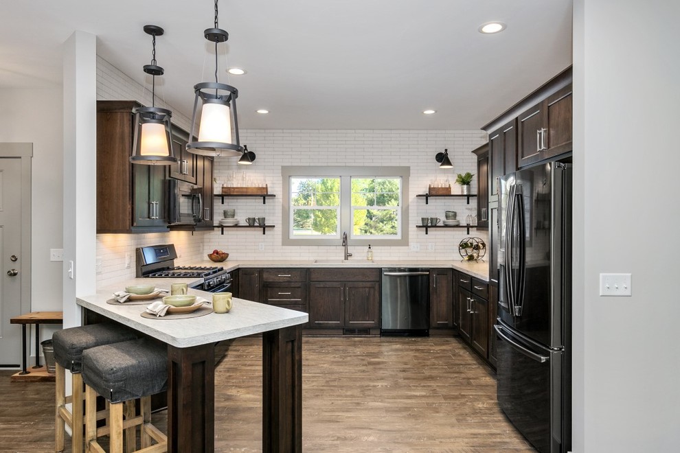 Traditional u-shaped open plan kitchen in Grand Rapids with a double-bowl sink, dark wood cabinets, laminate benchtops, white splashback, subway tile splashback, stainless steel appliances, laminate floors, beige benchtop and recessed-panel cabinets.