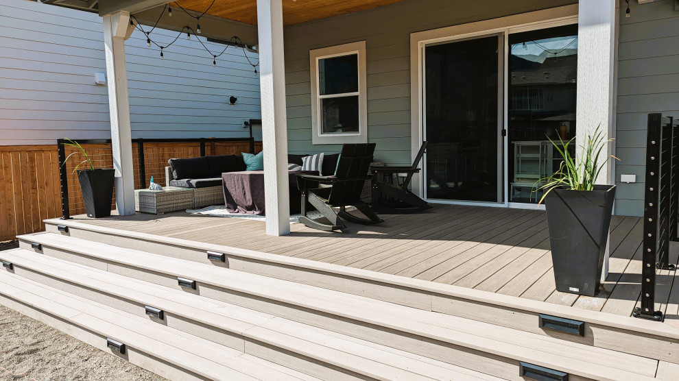 Photo of a mid-sized arts and crafts backyard and ground level deck in Seattle with an awning and cable railing.