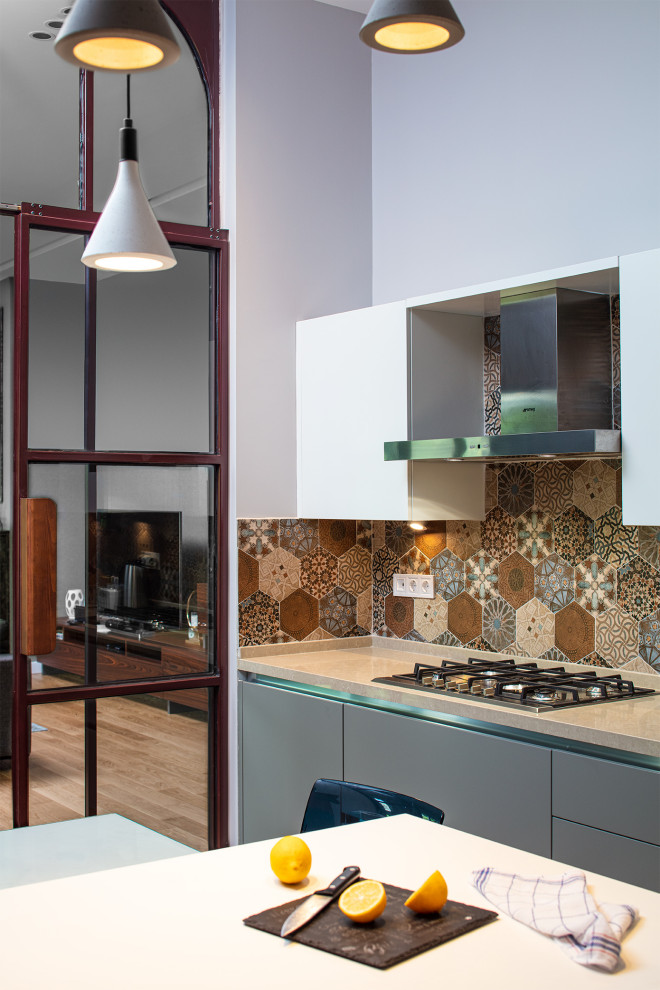 Photo of a mid-sized contemporary single-wall open plan kitchen in Other with quartzite benchtops, multi-coloured splashback, with island, beige benchtop, flat-panel cabinets, grey cabinets, mosaic tile splashback, medium hardwood floors and beige floor.