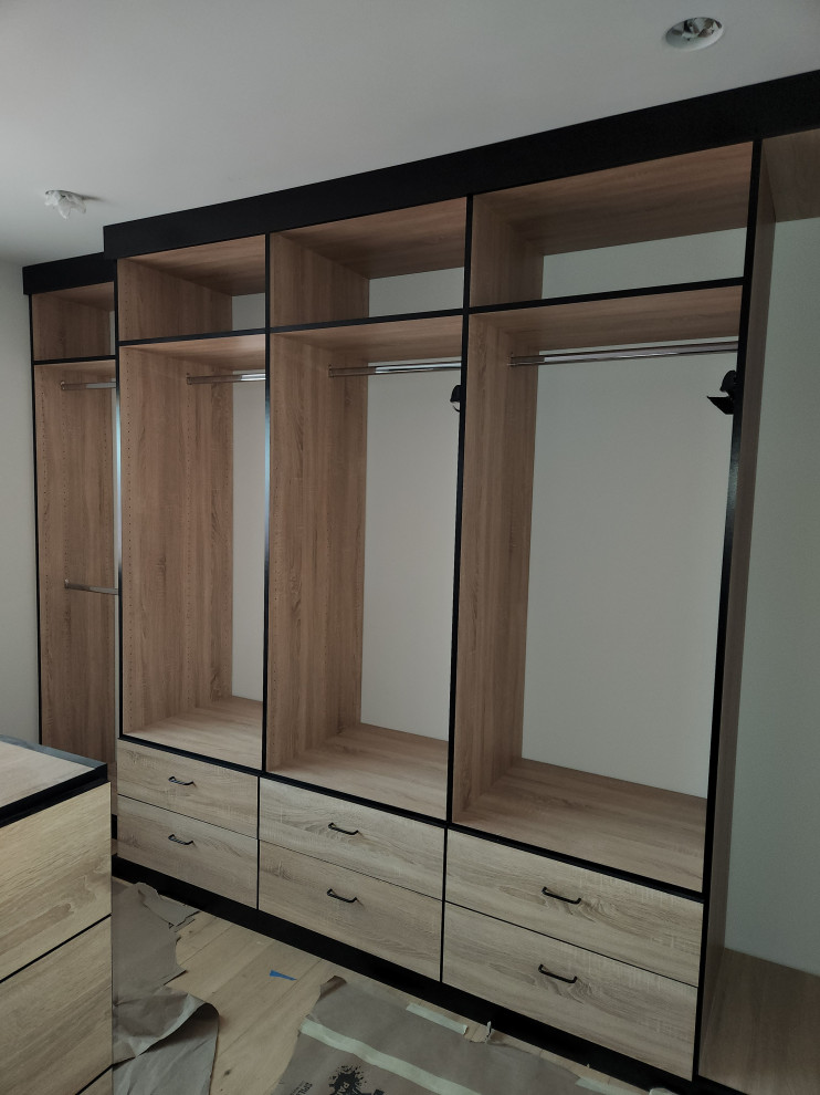Design ideas for a large walk-in wardrobe in Los Angeles with flat-panel cabinets, light wood cabinets and medium hardwood floors.